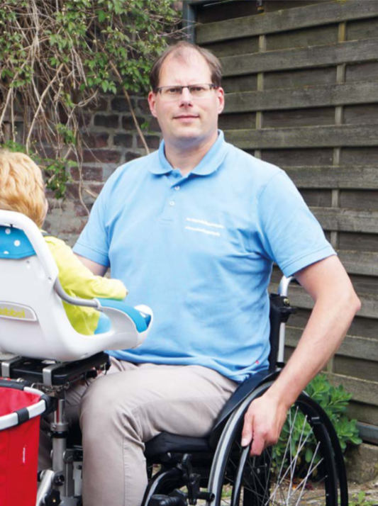 Mann im Rollstuhl mit Kind im Babysitz